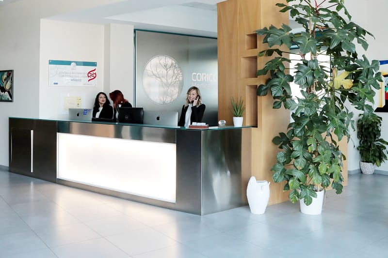L’accettazione: il banco illuminato, l’emblema dell’albero sulla parete e lo staff della segreteria
